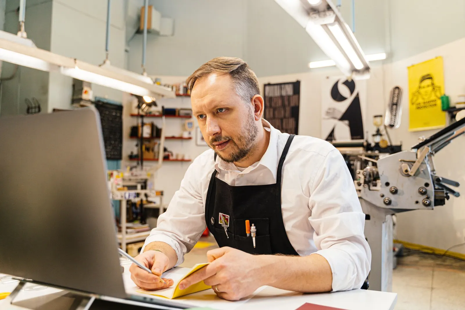 Inhaber arbeitet in seiner Werkstatt am Laptop