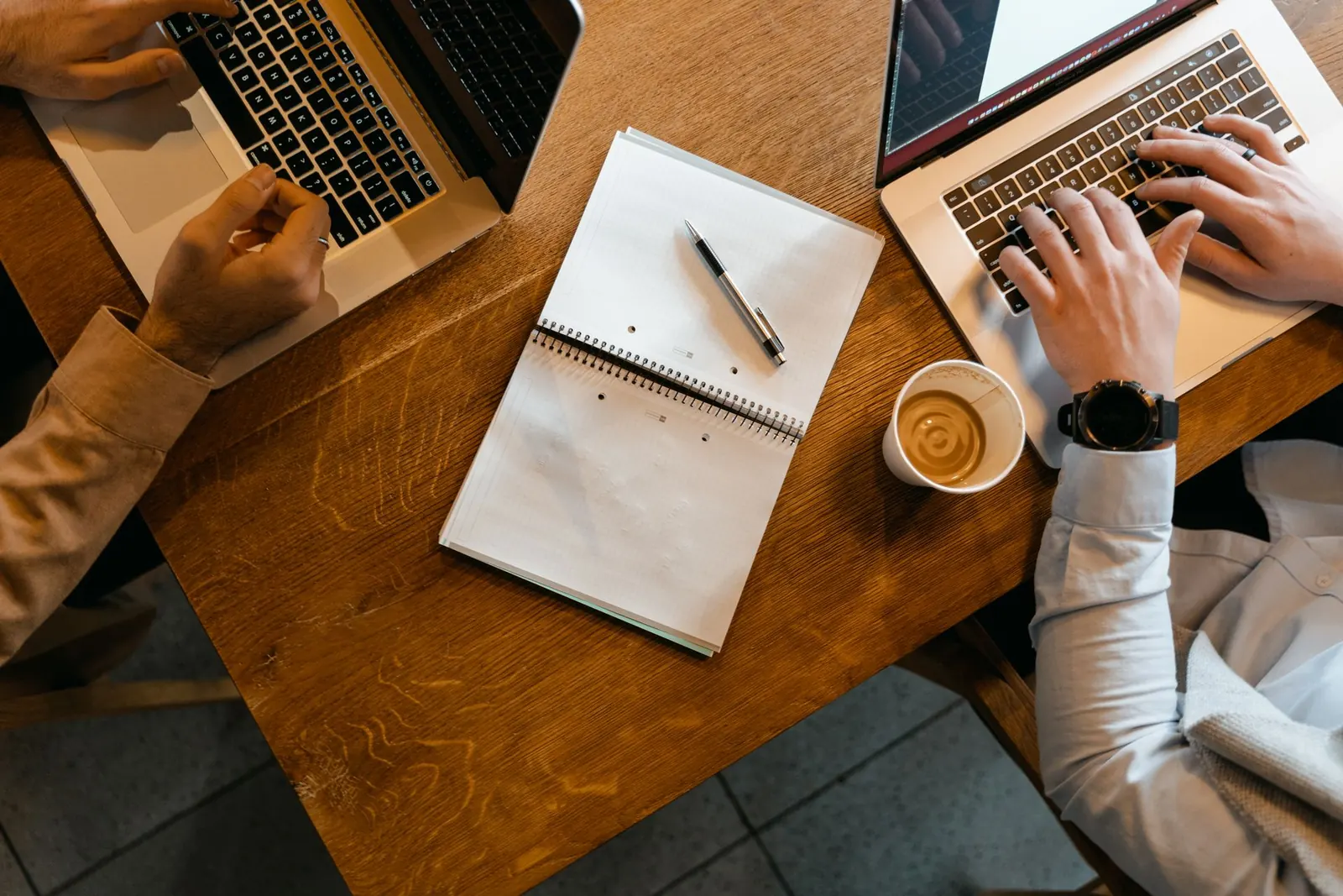 Zwei Personen arbeiten gemeinsam an Laptops, von oben fotografiert